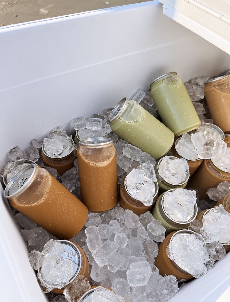 A cooler packed with crushed ice and canned coffee and matcha drinks