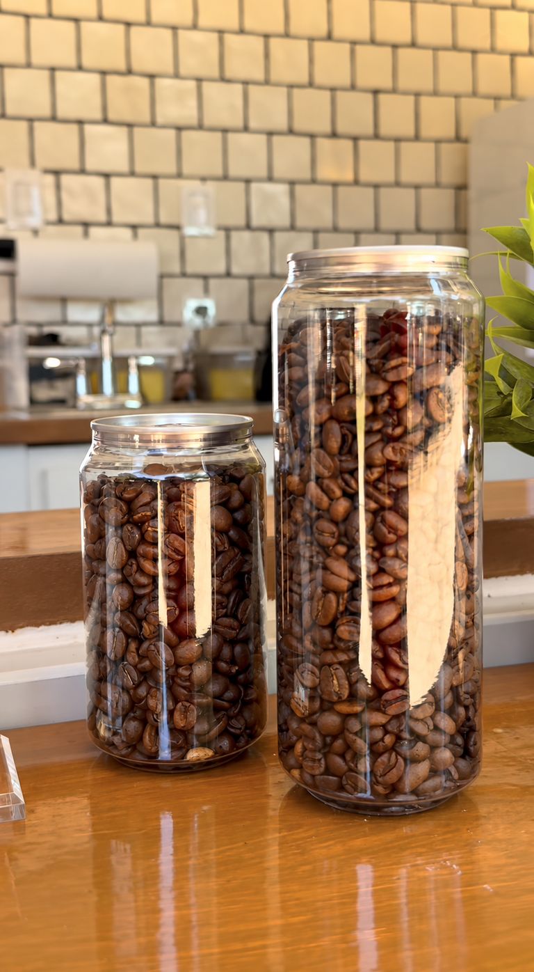 Two clear jars packed with roasted coffee beans on a wooden counter